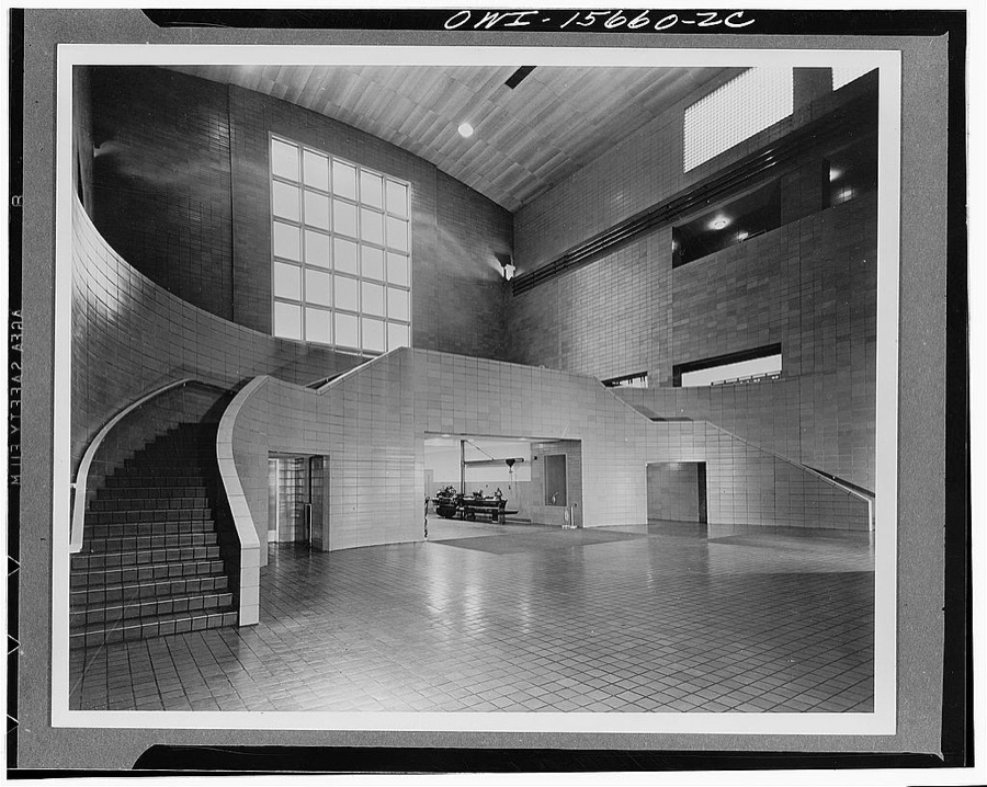 Guntersville Dam and powerhouse. View of entrance end of generator hall from generator floor. Raised platform at end serves as delivery and assembly space for machinery, also as visitors' overlook. Machine repair and electrical shops are located under platform. Offices in downstream wing are served by open corridor, beginning of which is seen on upper floor to the right of the picture. Directly below, control room which can be inspected from entrance platform. Windows of generator hall along sides are of glass brick (as at Chickamauga, also) for heat insulation and easier maintenance