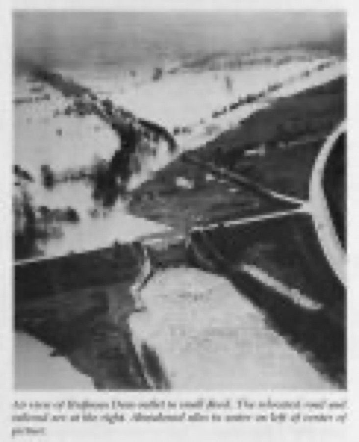 Air view of Huffman Dam outlet in small flood. The relocated road and railroad are at the right. Abandoned silos in water on left of center of picture