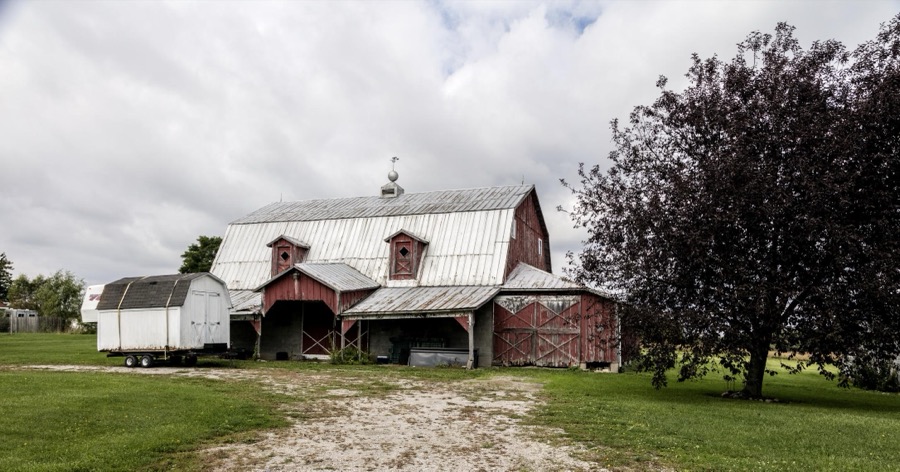 Old barn firmly affixed to the ground, and a smaller and much newer one (or more like a shed) on wheels on a farm in Williams County, Ohio