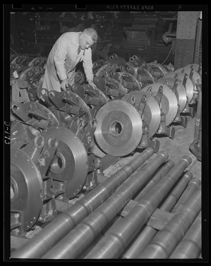 Production speeds up. Dozens of parts for anti-aircraft guns roll off the "line" in an eastern arsenal. Inspector checks finished top carriages for 37 mm guns