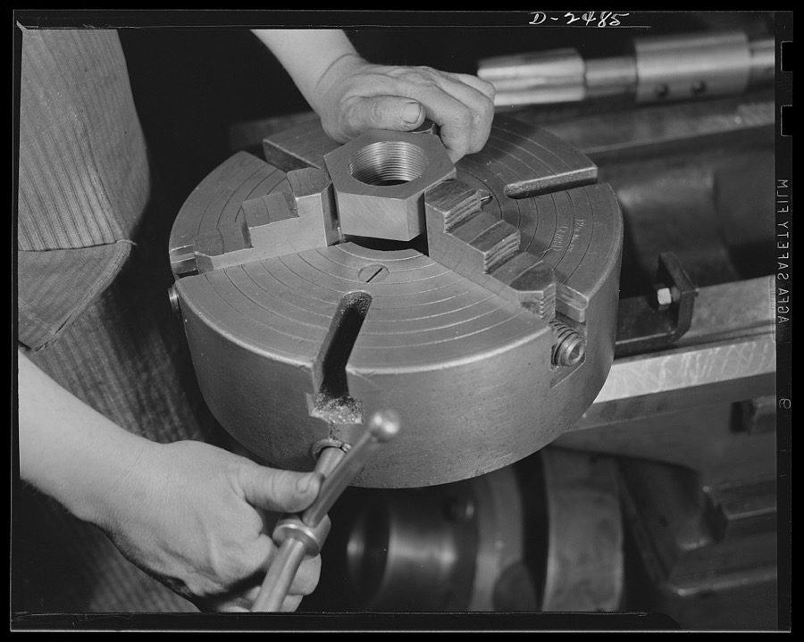 Conversion. Food machinery plant. This is a specially designed chuck for a newly acquired second-hand turret lathe, which this Eastern cube steak machinery plant recently bought from a nearby shoe factory in order to speed work on new defense subcontracts. Here it holds a three-and-a-quarter-inch hexagonal nut, which has just been threaded by the tap seen in the background. Cube Steak Machine Company, Boston, Massachusetts