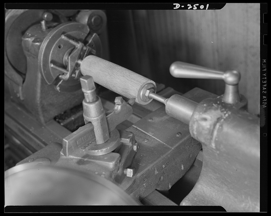 Conversion. Food machinery plant. Cutting of spouts for anti-tank guns is the present work of this lathe, shown here at its former job--shaping of wooden rollers used with a belt control to carry steaks into the cube steak machine which is this New England plant's normal product. Conversion of this lathe, and the stepping up of its speed, has turned his skill from peacetime work to war production. Cube Steak Machinery Company, Boston, Massachusetts