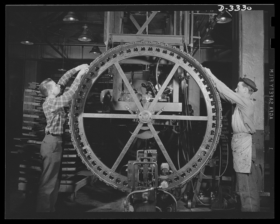The tracks for an Army halftrac scout car begins to take shape on the "building wheel" of a Midwest tire plant. Goodrich, Akron, Ohio