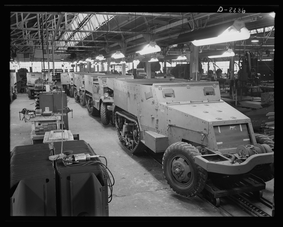Production. Halftrac armoured cars. Partly finished halftrac scout cars travel along a moving assembly line in a plant converted from the manufacture of safes and locks. The bodies are made in this plant and mounted on chassis produced in a converted automobile plant. Diebold Safe and Lock Company, Canton, Ohio