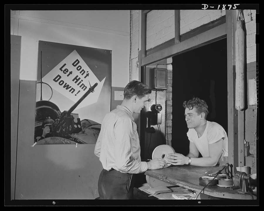 Barrage balloon manufacture. Getting supplies at the storehouse. This barrage balloon builder has come to the company's storehouse to obtain more reinforcing tape to fasten the seams of a barrage balloon. Small, but vital to production, every piece of material must pass over this counter and be recorded before issuance. The storekeeper is the only man who knows the secret formula for mixing the rubber cement combination which works most effectively in making air-tight seams. General Tire and Rubber Company, Akron, Ohio