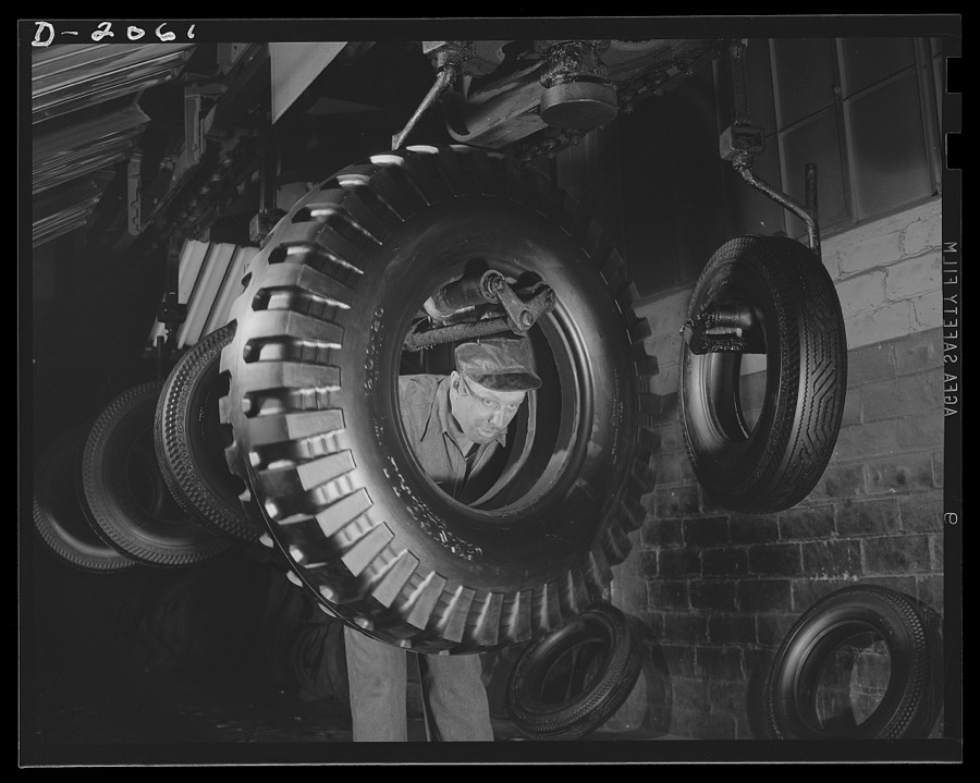 Through final inspection. Tires on an endless-crane overhead, swing through the final inspection department and spray paint booth where they are given a preservative coat of special tire paint. The tire-around-the-man is the new military tire--the non-directional. Firestone (General) Tires, Akron, Ohio