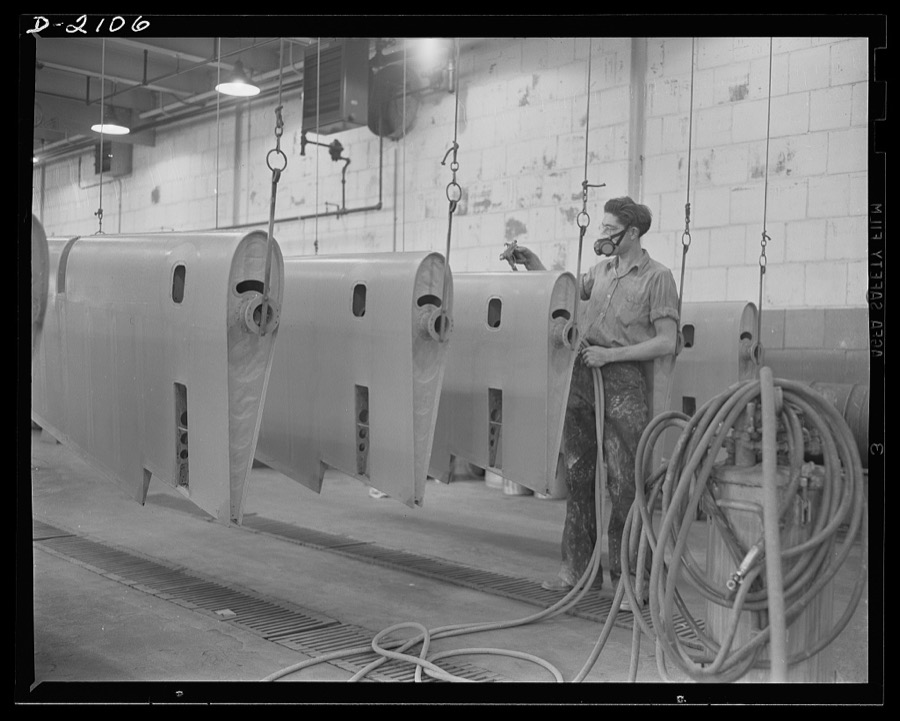 Subcontracting aircraft parts. Here is the "dope room" at a huge Ohio plant. The fabric covering control surfaces for military aircraft is here doped, or covered with protective paints. This worker is spraying  surfaces with a special lacquer to make them glossy and weather-proof. Goodyear, Akron, Ohio