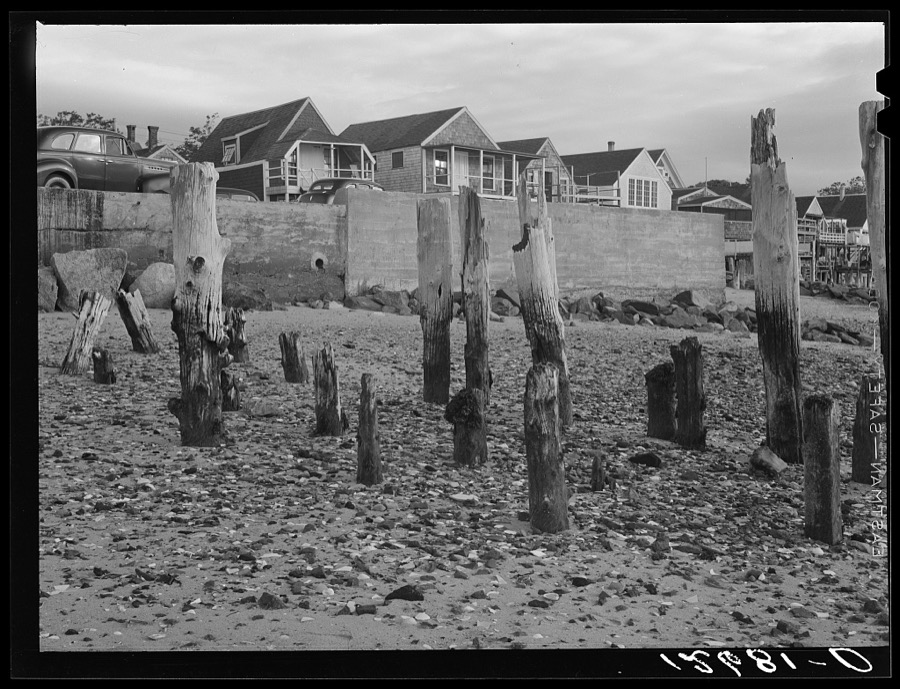 Ruins of fish pier with breakwater and new tourist cottages in the background. Provincetown, Massachusetts