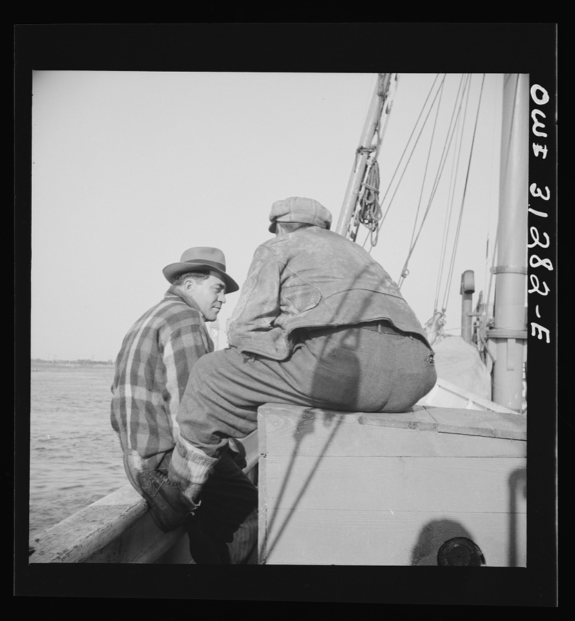 On board the fishing boat Alden out of Gloucester, Massachusetts. Fishermen sitting about the deck on the first morning