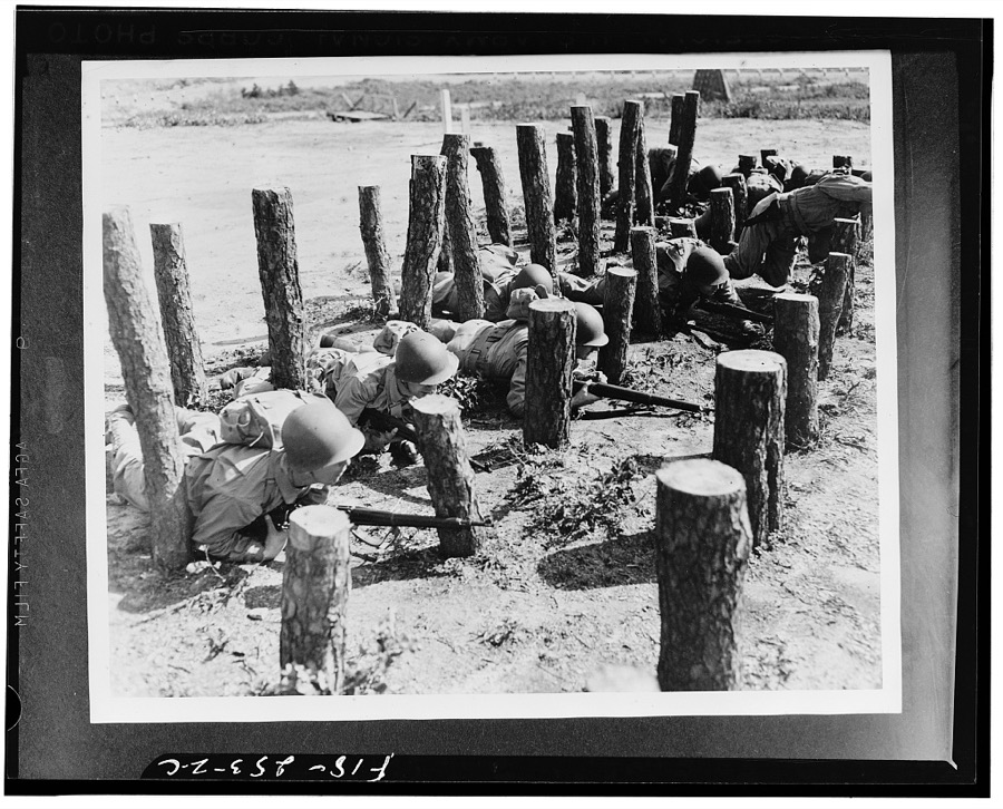 Camp Edwards, Massachusetts. This "asparagus patch," consisting of pine logs stuck in the ground, is an obstacle that looks easy but in reality is a backbreaker. Men must be able to crawl for some distance, twisting and turning like a snake, to complete this course, for the logs are set in a straight line