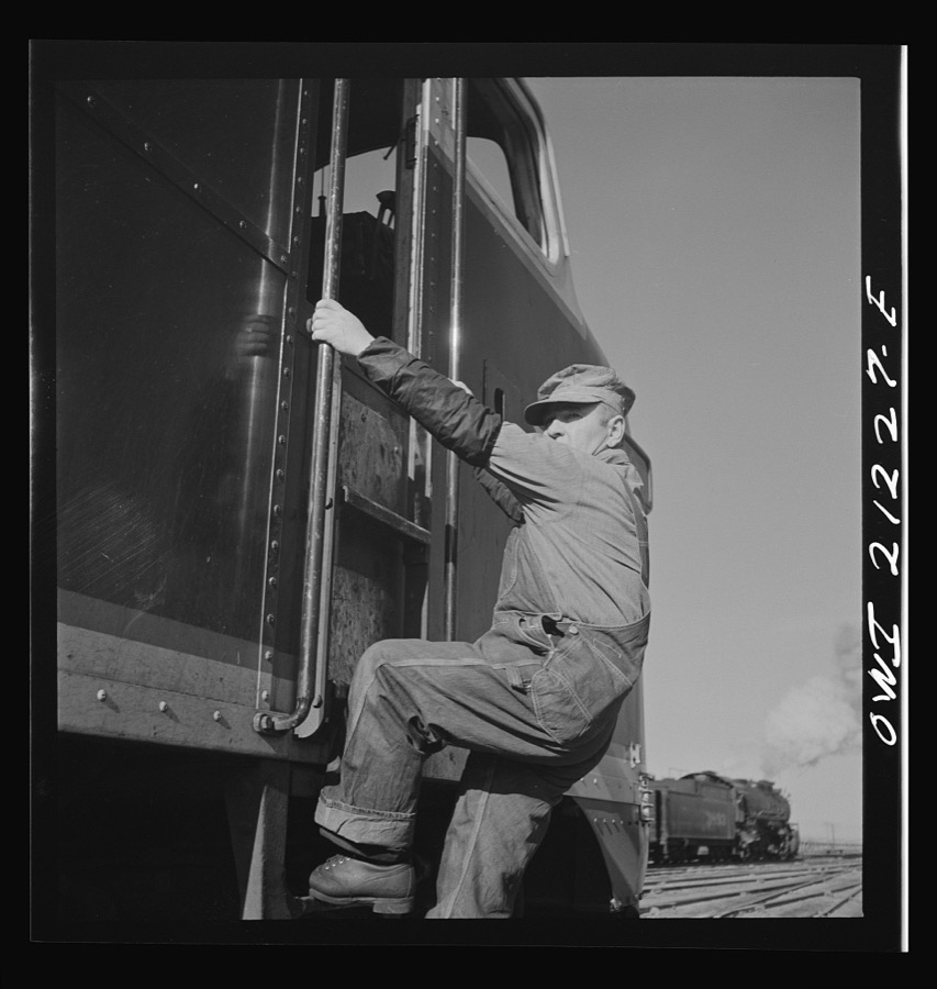 Winslow, Arizona. Engineer George Bertino climbing into the cab of a diesel freight engine in the Atchison, Topeka and Santa Fe Railroad yard