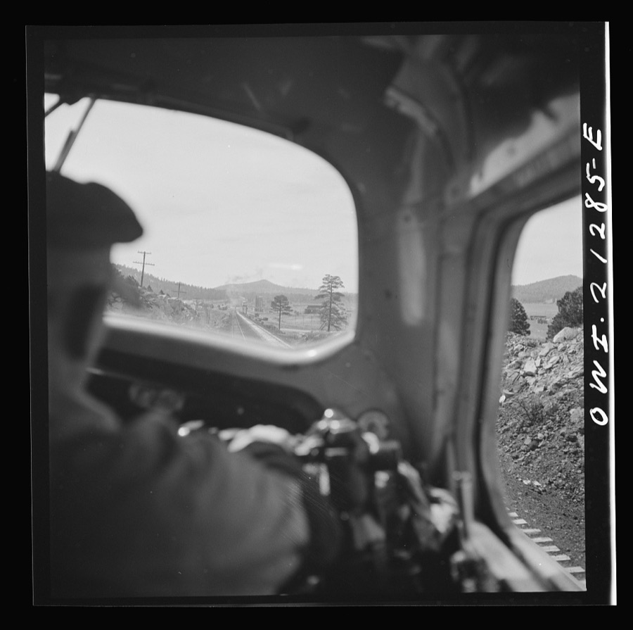 Willliams, Arizona. The engineer, on the Atchison, Topeka and Santa Fe Railroad between Winslow and Seligman, Arizona, with his hand on the "air" as the train slows down