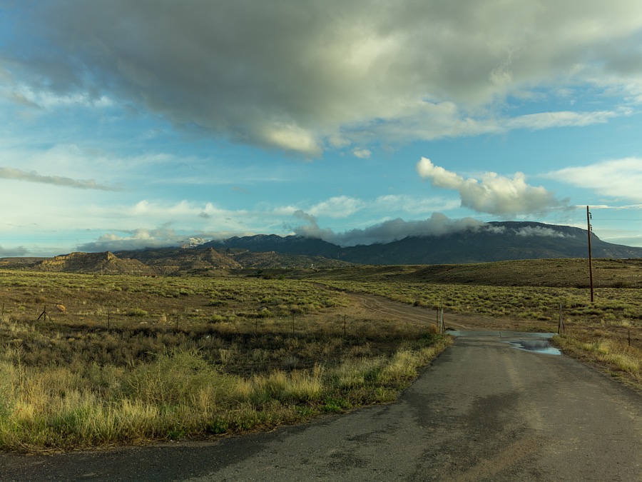 A roughly paved road turns to dirt past a cattle guard near the tiny settlement of Teec Nos Pos, Navajo for "Cottonwoods in a Circle", in the far-northeast corner of Arizona, in Navajo County