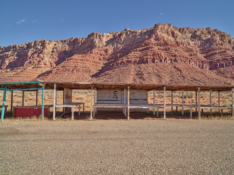 A faded and flaking image of a man appears on an abandoned Indian jewelry or pottery stall near Cameron, Arizona