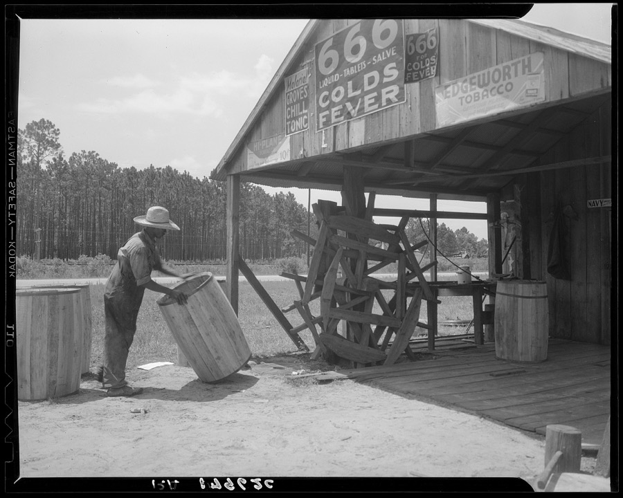 Turpentine still near Valdosta, Georgia. The "cooper" makes barrels to hold the gum