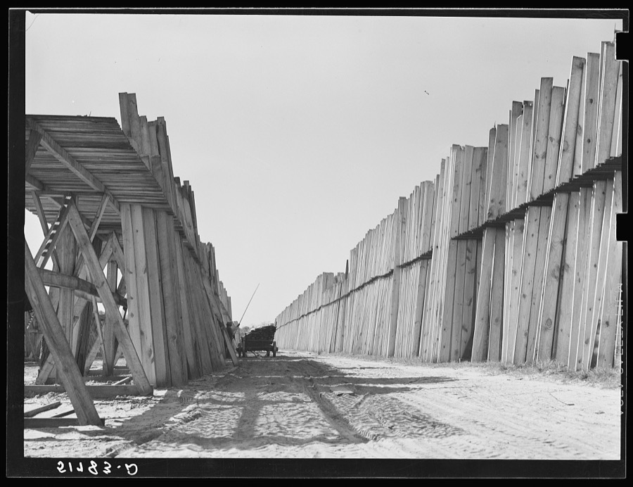 Stacks of lumber with tractor in planing mill. Cairo, Georgia