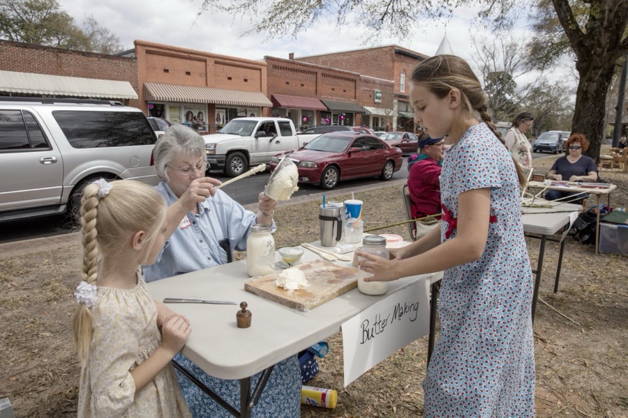 Elsie Unruh, left, and Blaine Holdeman observe Patricia Edwards as she demonstrates country-style butter maning during Heritage Day n Louisville, a town in northeastern Georgia, named for French King Louis XVI in appreciation for French assistance to the colonists during the American Revolution