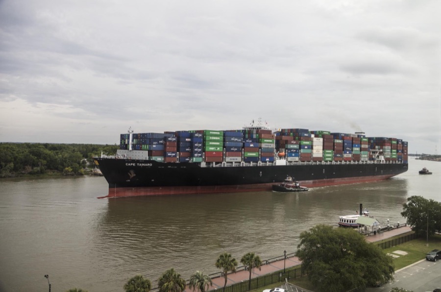 With a tugboat's help, an exceptionally heavy-laden oceangoing container ship plies the busy Savannah River in Savannah, Georgia