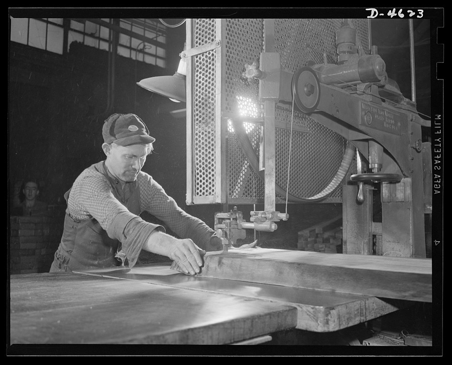 Conversion. Flooring to gunstocks. Cutting gunstock blocks for the Army. A walnut slab, or flitch, is run through a band saw, and marked sections are cut out with precision. The final clear pieces, of gunstock dimension, will later be cut from these sections by the ripsaws of a converted flooring plant