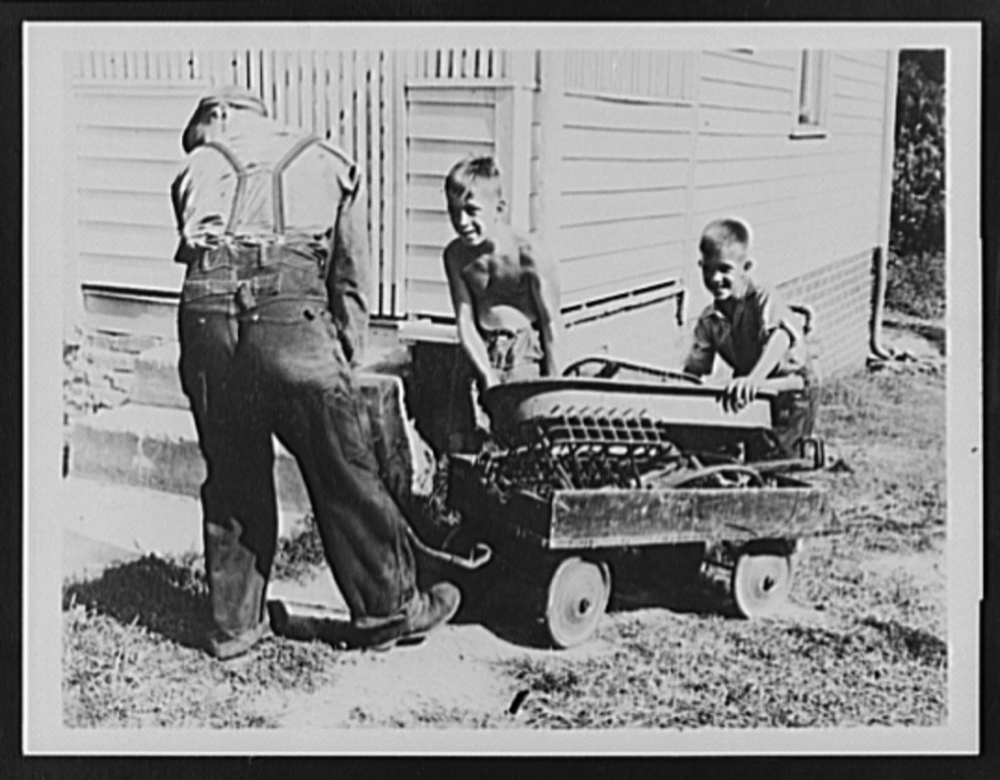 Ashland, Kentucky. Two boys who have gathered up iron scrap for the war effort being assisted by a scrap collector in moving the load in their coaster wagon