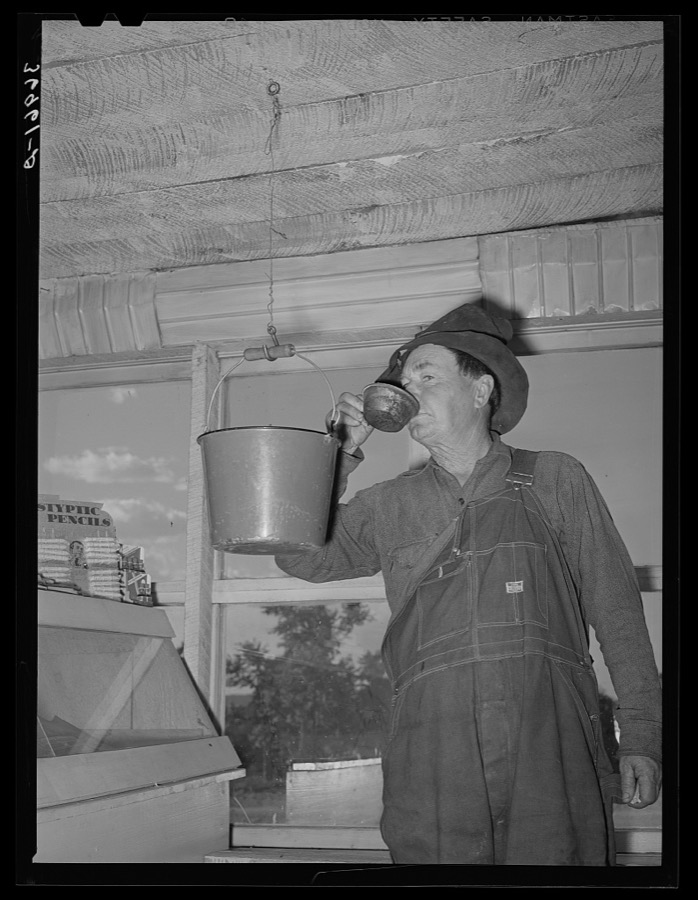 Farmer drinking water from bucket which hangs in the general store. Pie Town, New Mexico
