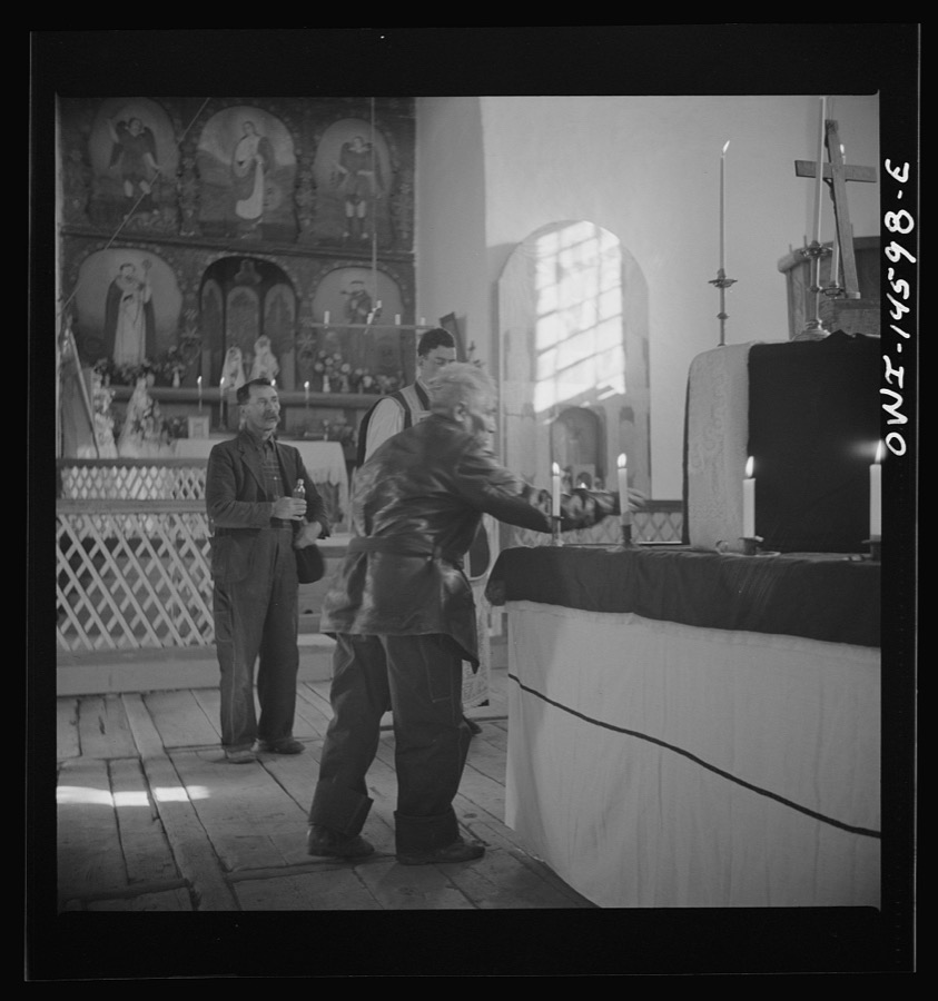 Trampas, New Mexico. Member of the congregation leaving an offering during a memorial mass in church which was built in 1700 and is the best-preserved colonial mission in the Southwest