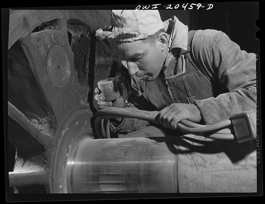Albuquerque, New Mexico. Magnaflux inspector A.J. Fry at work on an engine wheel axle in the Atchison, Topeka and Santa Fe Railroad shop. The cable in his hand magnetizes the axle as he spreads steel dust over an area. He then cuts the current off and carefully blows the dust away. The steel particles remain, however in any tiny cracks and reveal any surface flaws that might exist. Axles of engine wheels are magnafluxed every 200,000 miles