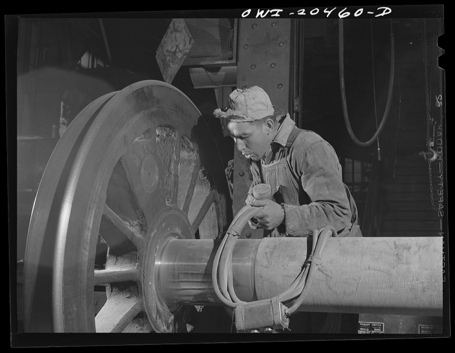 Albuquerque, New Mexico. Magnaflux inspector A.J. Fry at work on an engine wheel axle in the Atchison, Topeka and Santa Fe Railroad shop. The cable in his hand magnetizes the axle as he spreads steel dust over an area. He then cuts the current off and carefully blows the dust away. The steel particles remain, however in any tiny cracks and reveal any surface flaws that might exist. The axles of engine wheels are magnafluxed every 200,000 miles
