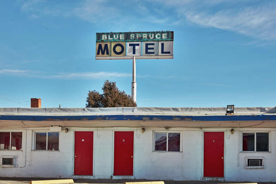 A sign for one classic motel, the Blue Spruce, on historic U.S. Route 66 in Gallup, a small city near the Arizona border in far-western New Mexico towers above the actual quarters of its next-door neighbor, the Lariat Lodge