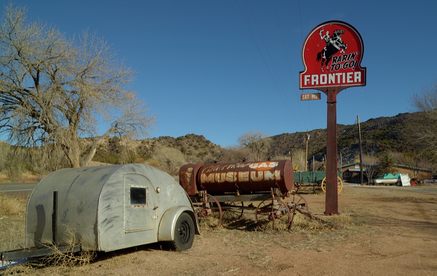An old camper stands beneath a Frontier Gasoline station sign at a nostalgic roadside attraction, the Classical Gas Museum, in the Rocky Mountain foothills of northern New Mexico, near the town of Dixon