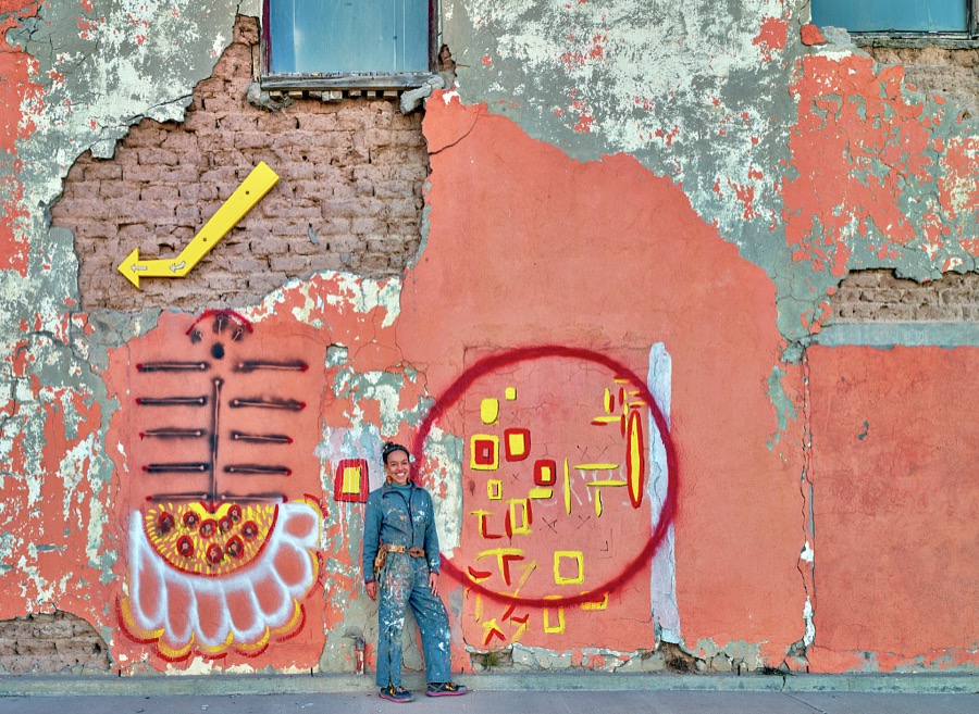 The paint spatters on artist Paula Wilson's work-clothes accent the worn but colorful façade of the Lyric Theatre in the small south-central New Mexico town of Carrizozo, with a population of 1,000 or so (as of 2021)