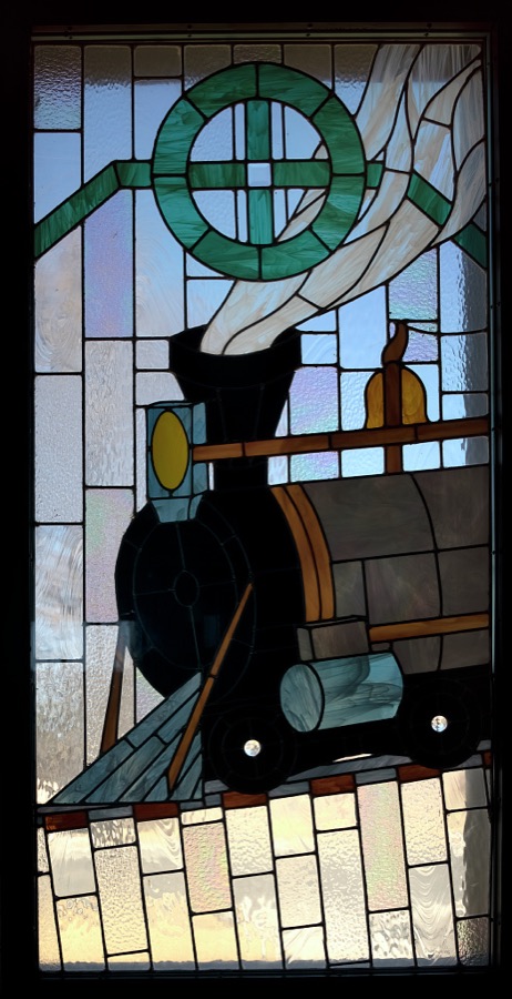 An elaborate stained-glass window depicting a steam locomotive, down to the steam itself, at the 1910 Las Cruces, New Mexico, train depot