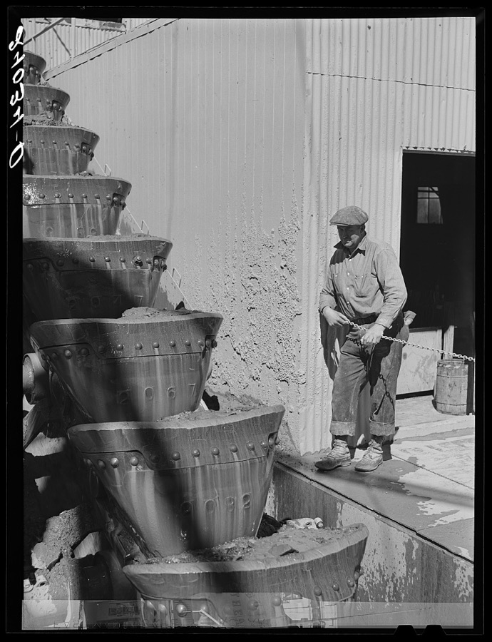 Gold dredge worker watches the buckets lifting the ore into the dredge. Nye County, Nevada