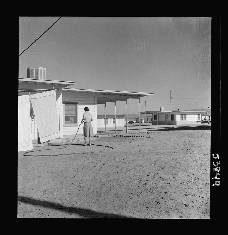 Las Vegas, Nevada. A worker's wife watering a newly planted lawn around one of the thousand demountable houses built adjacent to the Basic Magnesium Incorporated plant in the southern Nevada desert