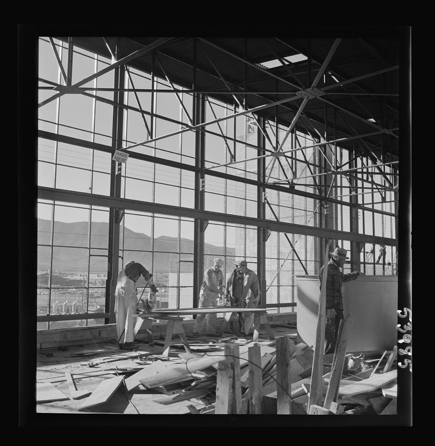 Las Vegas, Nevada. Workmen busy with woodwork inside the steel structure of one of the buildings of the Basic Magnesium Incorporated plant. Much of the plant can be seen in the background, and beyond it loom high mountains