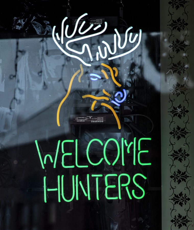 A neon sign welcoming hunters in the old mining town of Pioche, which appears to hang along the side of a mountain and in a bowl below in Nevada's high desert, near the state's eastern border with Utah
