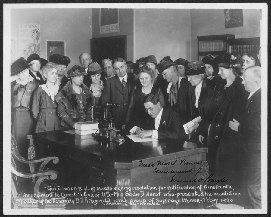 Gov[ernor] Emmett D. Boyle of Nevada signing resolution for ratification of Nineteenth Amendment to Constitution of U.S. - Mrs. Sadie D. Hurst who presented the resolution, Speaker of the Assembly D.J. Fitzgerald and group of Suffrage Women, Feb. 7, 1920, Carson City, Nevada
