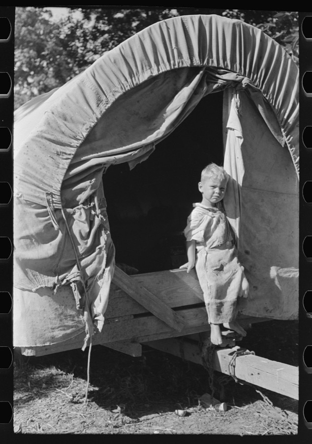 Son of white migrant stepping from covered wagon-type trailer, Wagoner County, Oklahoma