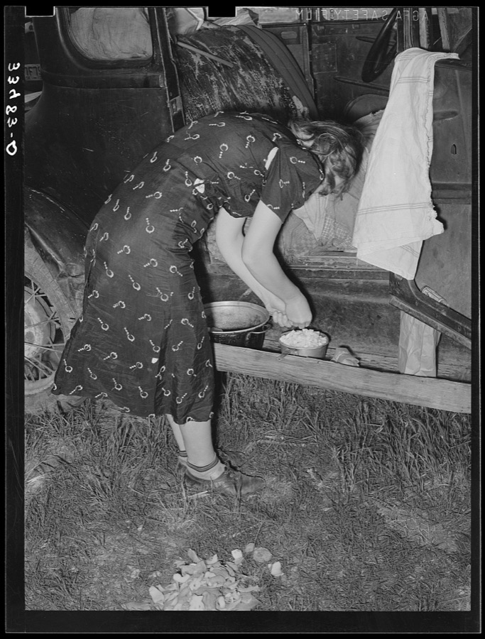Migrant woman peeling potatoes on running board of car while camped near Prague, Oklahoma. Lincoln County, Oklahoma