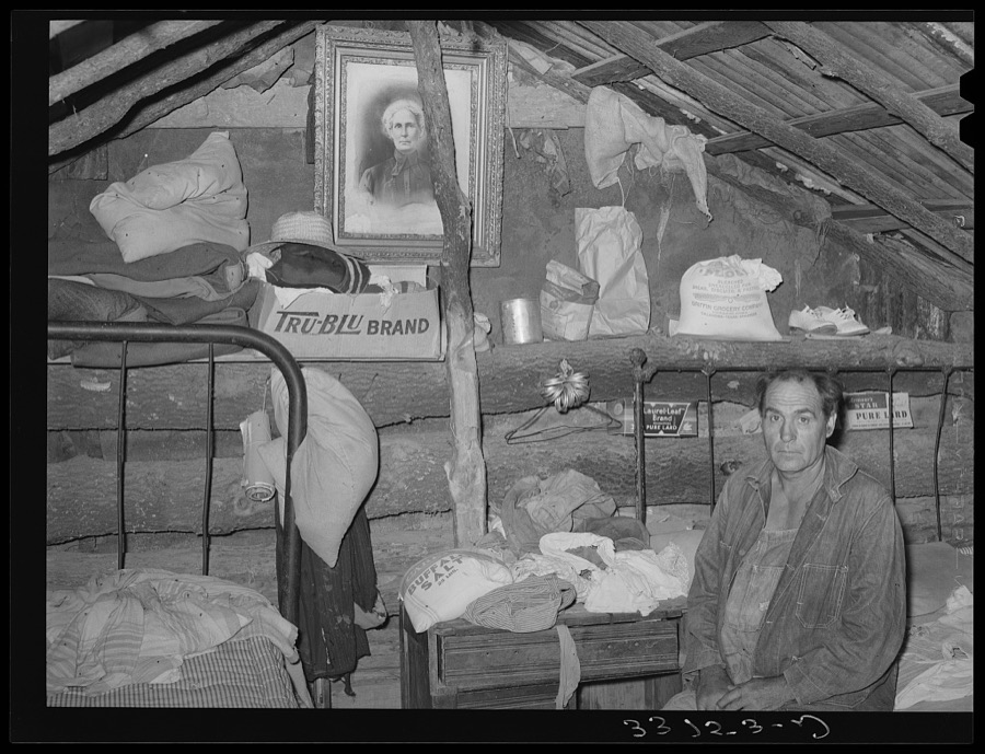 Indian agricultural worker in his home with portrait of his mother. McIntosh County, Oklahoma