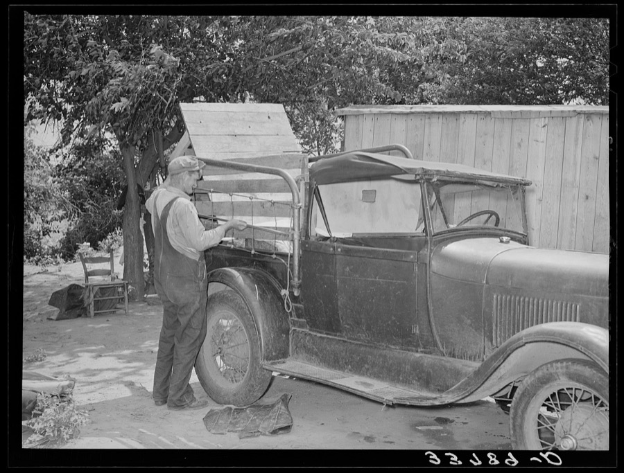 Packing and securing bedsteads on side of truck which will carry this migrant family to California from Muskogee, Oklahoma