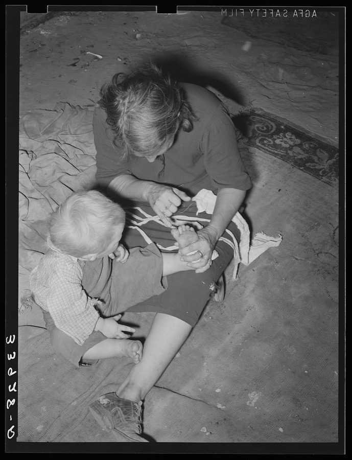 Mother of child pointing to his cut toe, injured while playing in trash and debris of camp. Mays Avenue camp, Oklahoma City, Oklahoma
