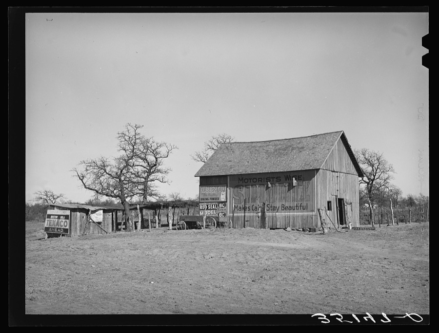 Barn and vegetable stands of Pomp Hall, Negro tenant farmer. During the summer months he sells his produce at this stand on the highway. He also adds to his income by allowing the signs to be painted on his barn which is visible far down the highway. Creek County, Oklahoma. See general caption number 23
