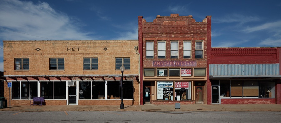 A block of mostly vacant stores, save for a loan office, in Anadarko, a small city in southwest Oklahoma that (as of 2020) has been struggling with dropping population, increasing unemployment and a downturned local economy