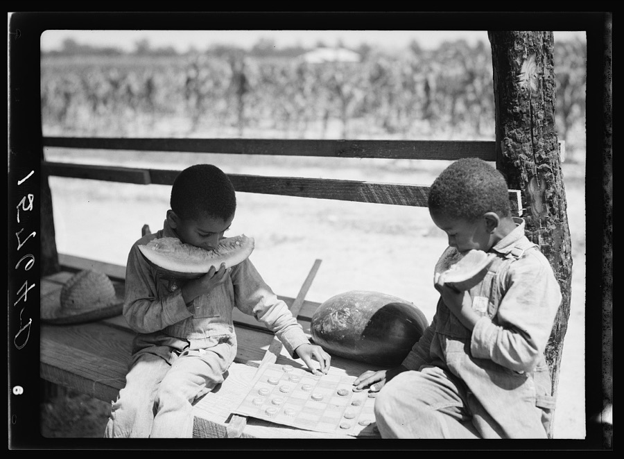 Negro boys eating watermelon and playing checkers with bottle caps. Florence County, South Carolina