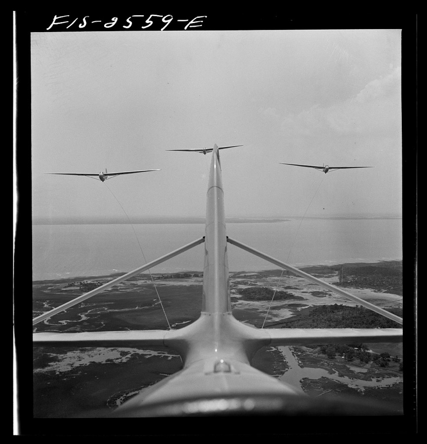 Parris Island, South Carolina. U.S. Marine Corps glider detachment training camp. An aerial "tug boat" tows three gliders high above the field