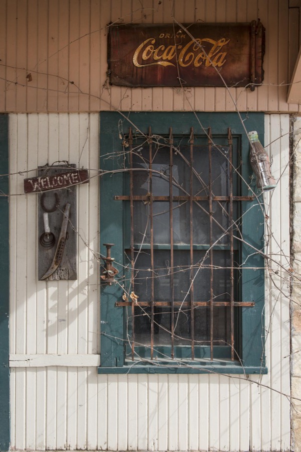 The sign says "Welcome," but the vines tell another story at an old gas station near Pipe Creek in Bandera County, Texas