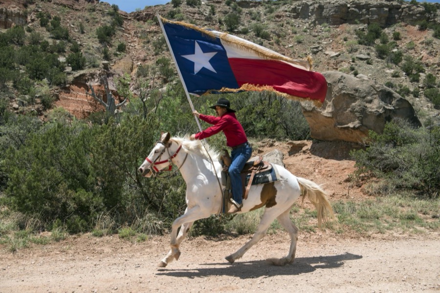 A highlight of the "Texas" outdoor musical drama, staged in the Pioneer Amphitheater carved from the rocks of Palo Duro Canyon southeast of Amarillo in the Texas Panhandle, are majestic rides along the canyon rim by Paul Lundergeen, aboard his white stallion, Ghost. Following his initial gallop, more than 60 performers take the stage to tell the story of the Lone Star State in song and dance