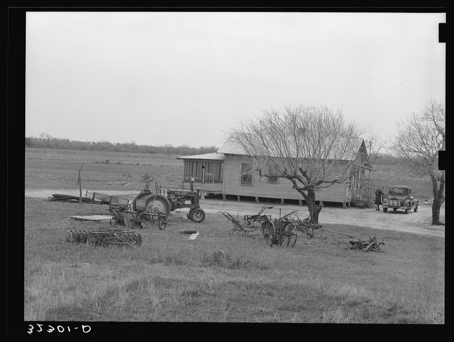 Farmhouse of small farmer near Santa Rosa, Texas. Tractor and rusting farm implements are in the yard, showing the changes in farming methods and also demonstrating that even the small farmers are using the new tractors and other mechanized equipment