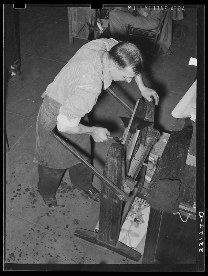 Placing pieces of leather into crimping machine to shape the lowers of the boots. Boot shop, Alpine, Texas